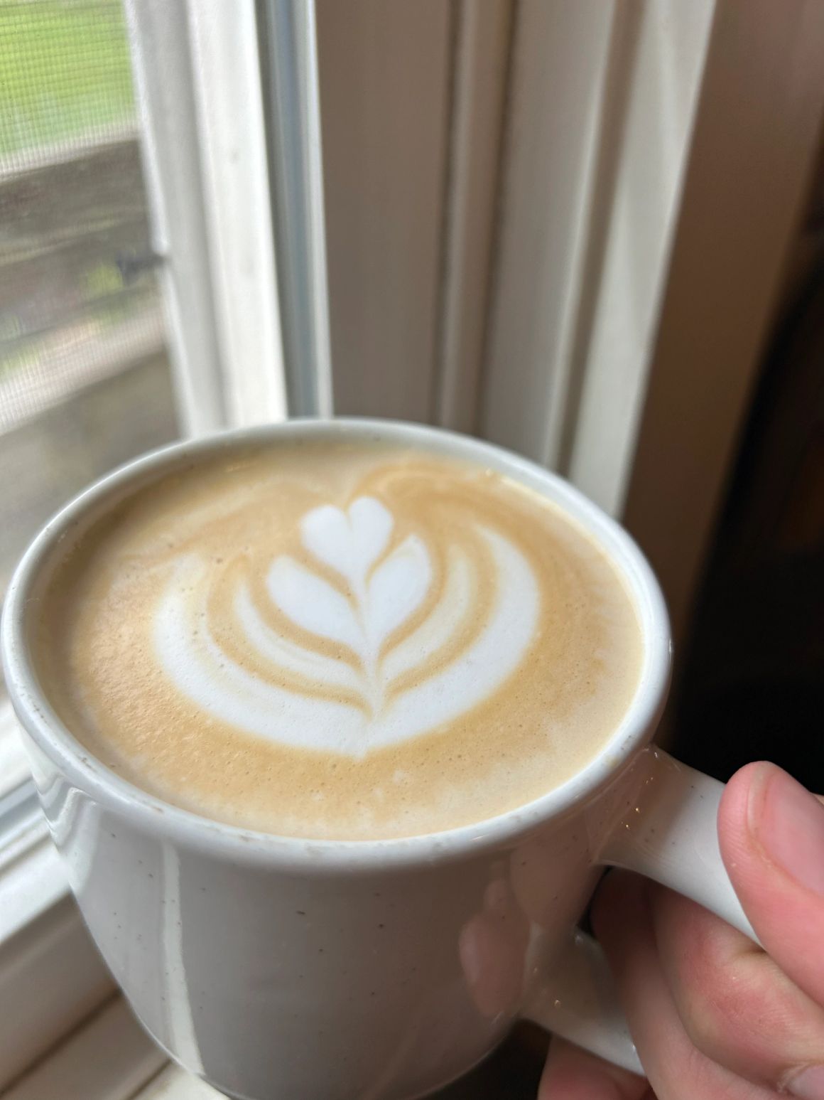 Latte with heart art in a Mocha Lisa mug by the window
